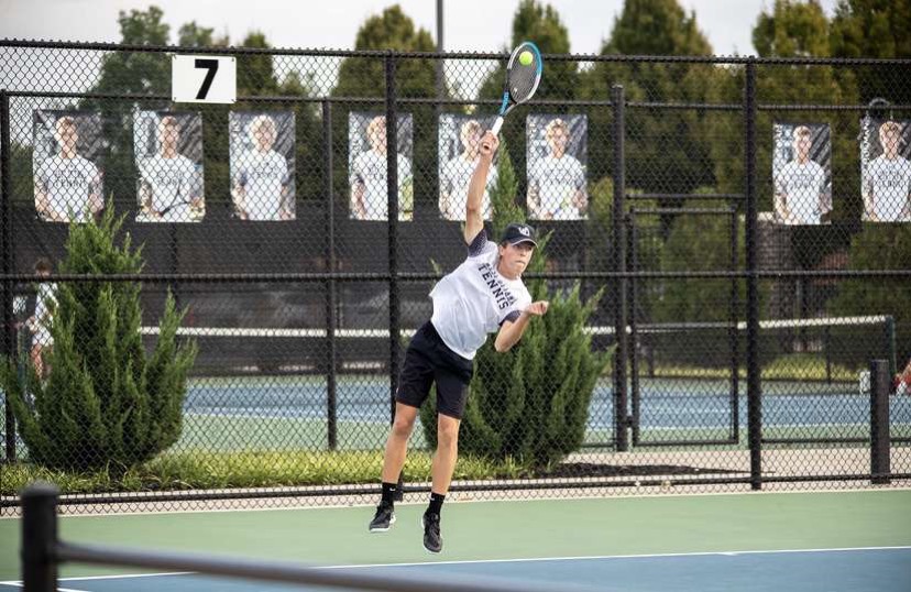 Jr. Elliot Dozeman in the middle of his serve at a home match.