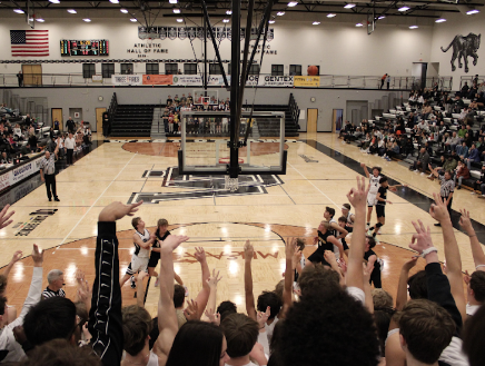 Jr. Danny Siterlit shooting a 3-pointer with the student section supporting.